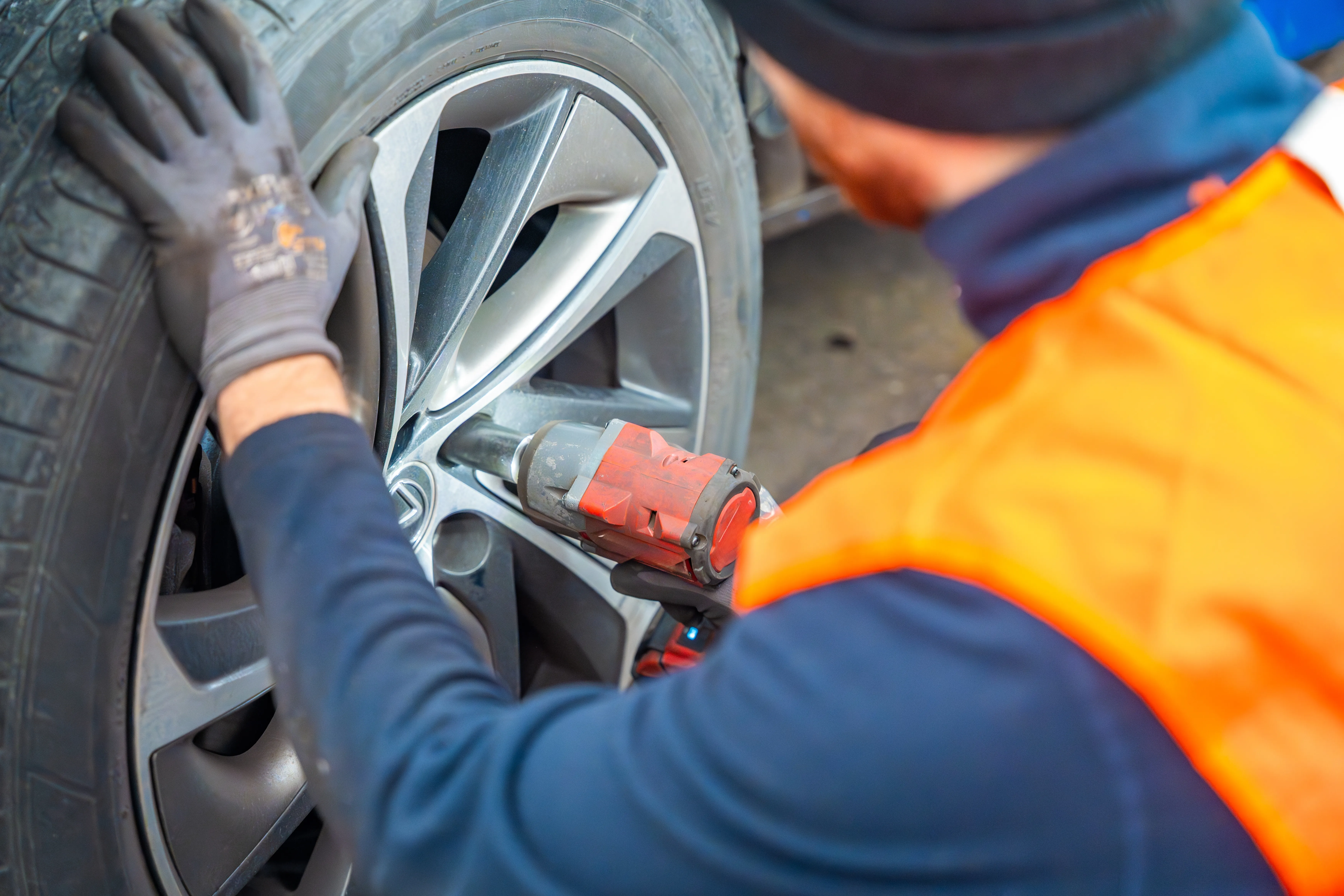 Mobilna wymiana kola — mechanik dokreca sruby kluczem udarowym